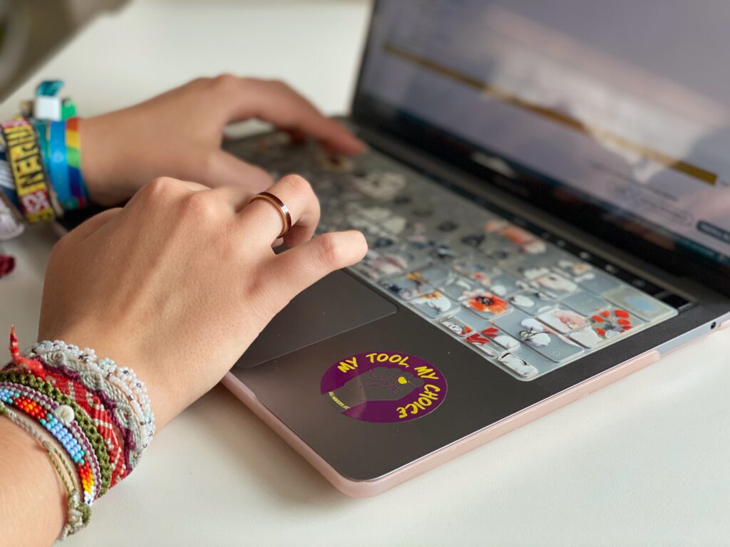 Purple sticker reading “My tool, my choice,” featuring a transparent fist, attached to a laptop used by a female maker.